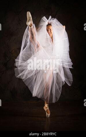 Donna snella in un corset bianco tutu balletto da ballo. Riprese in studio su sfondo scuro, immagini isolate. Foto Stock
