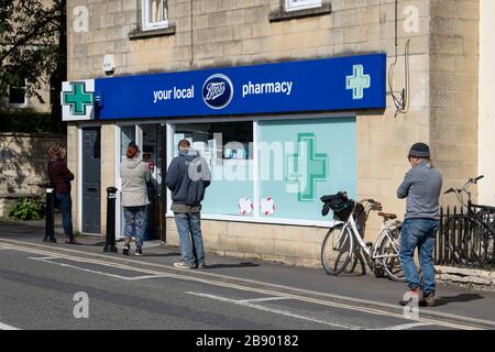 Le persone si accodano al di fuori di una farmacia Boots nel Somerset, poiché le misure di distanza sociale hanno effetto in tutto il Regno Unito per cercare di combattere l'epidemia di Coronavirus. Foto Stock