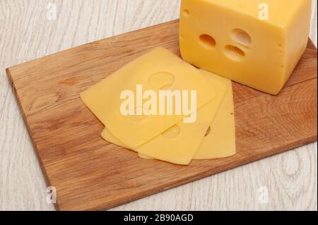 Pezzo di formaggio e formaggio a fette su un asse di legno Foto Stock