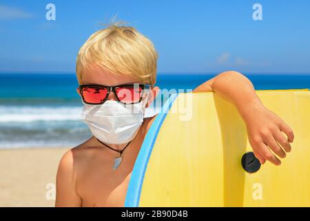 Giovane surfista che indossa occhiali da sole, maschera protettiva sul viso  corsa sul surf. Escursioni estive in spiaggia, crociere cancellate a causa  dell'epidemia di coronavirus COVID-19 Foto stock - Alamy