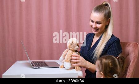 La mamma che lavora lavora da casa. Felice madre e figlia sorridente. Donna di successo e bambino carino che usa il notebook. Ambiente di lavoro libero. Femmina Foto Stock