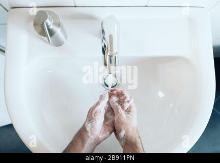 vista dall'alto della persona lavando accuratamente le mani al lavandino del bagno con sapone e acqua calda, misure igieniche durante il coronavirus covid-19 pandemic per prevenire Foto Stock