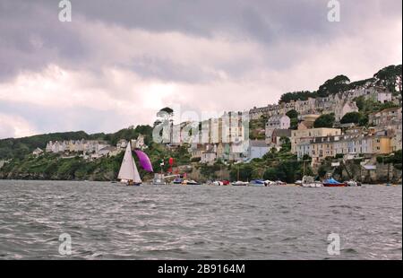 Fowey dall'estuario, con una classe Troia keelboat T5 'Amethyst', costruito nel 1930 che corre nel porto sotto spinnaker: Corwall, Inghilterra, Regno Unito Foto Stock