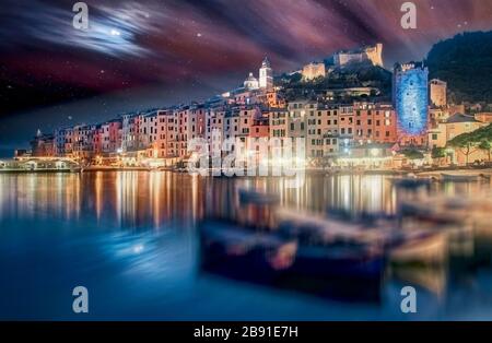 Vista sulla baia e sui pescherecci ormeggiati di Portovenere, la Spezia, Liguria, Italia al crepuscolo con riflessi delle luci del Mediterraneo Foto Stock