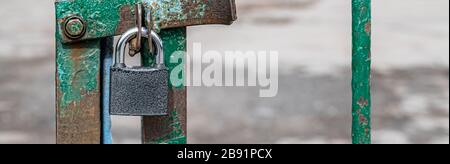 Griglia della porta chiusa e bloccata con lucchetto color argento. Un blocco in metallo sulle cerniere è appeso in primo piano sulla griglia. Concetto di sicurezza o divieto, spazio di copia per il Foto Stock