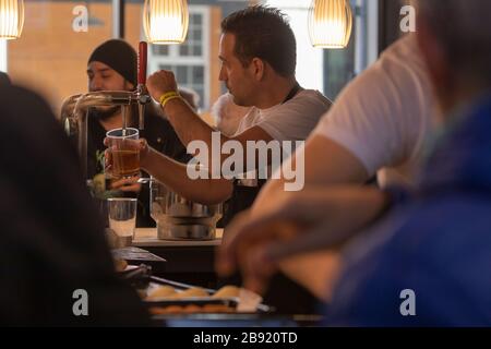 Saragozza, Spagna - 6 febbraio 2020: Un barman prepara una birra per alcuni clienti in un tapas bar situato nel mercato centrale di Saragozza o Lanuza. Foto Stock