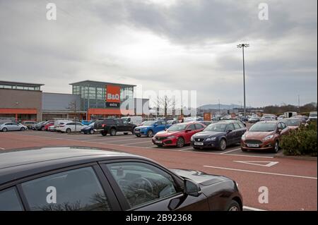 Edimburgo, Scozia, Regno Unito. 23 marzo 2020. B&Q e Screwfix, i negozi del Regno Unito di Kingfisher rimarranno aperti con orari di apertura ridotti nonostante la pandemia di coronavirus. Nella foto è stato raffigurato il parcheggio del New Craighall Retail Park con un parcheggio molto trafficato, forse in attesa di persone costrette a rimanere a casa i lavori di giardinaggio e fai da te possono essere fatti. Anche il numero di clienti ammessi nel negozio è stato limitato. Foto Stock