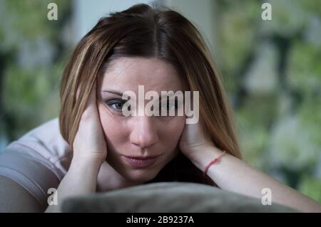 Donna millenaria penosa che guarda blankly nella macchina fotografica. Donna che guarda la TV a casa. Annoiato donna sul divano Foto Stock