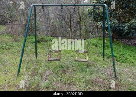 Altalene arrugginite in un parco giochi per bambini troppo cresciuto abbandonato. Foto Stock