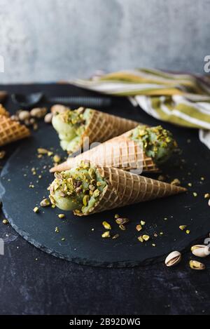 Primo piano di gelato al pistacchio in coni su sfondo nero. Foto Stock