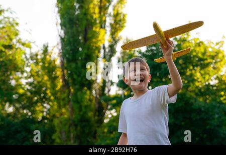 Il ragazzo lancia un aliante giocattolo al tramonto. Sfondo morbido. Foto Stock