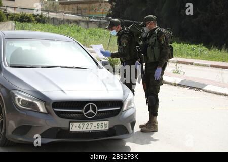 23 marzo 2020: Jenin, West bank. 23 marzo 2020. I membri delle forze di sicurezza nazionali palestinesi hanno costituito una barriera e hanno fatto controlli all'ingresso della città di Jenin per applicare l'attuazione di nuove misure restrittive contro la diffusione del coronavirus in Cisgiordania. Domenica il primo Ministro palestinese ha ordinato un divieto di due settimane su tutti i movimenti non essenziali per contenere la diffusione di Covid-19, mentre il numero di casi confermati in Cisgiordania è salito a 57 Credit: Mohammed Turabi/IMAGESLIVE/ZUMA Wire/Alamy Live News Foto Stock