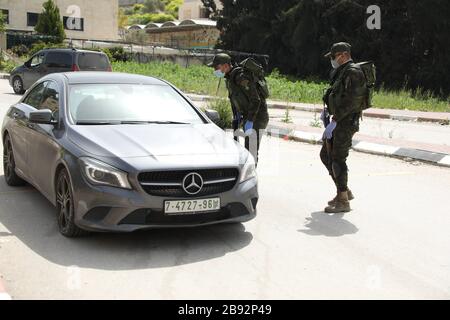 23 marzo 2020: Jenin, West bank. 23 marzo 2020. I membri delle forze di sicurezza nazionali palestinesi hanno costituito una barriera e hanno fatto controlli all'ingresso della città di Jenin per applicare l'attuazione di nuove misure restrittive contro la diffusione del coronavirus in Cisgiordania. Domenica il primo Ministro palestinese ha ordinato un divieto di due settimane su tutti i movimenti non essenziali per contenere la diffusione di Covid-19, mentre il numero di casi confermati in Cisgiordania è salito a 57 Credit: Mohammed Turabi/IMAGESLIVE/ZUMA Wire/Alamy Live News Foto Stock