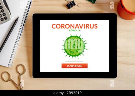 Coronavirus, concetto covid-19 su schermo tablet con oggetti da ufficio su scrivania in legno. Distanza sociale. Vista dall'alto Foto Stock