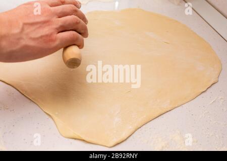 Stendete l'impasto. il panettiere stira l'impasto su un tavolo di legno cosparso di farina Foto Stock