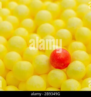 Palline di polistirolo colorate gialle e rosse. Concettuale per l'autoisolamento di Covid-19, portatore di malattie, persona infetta, isolata, persa nella folla. Foto Stock