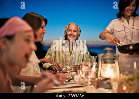Famiglia gustando una cena all'aperto sul loro retro deck. Foto Stock