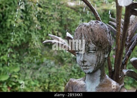 Scultura di una giovane ragazza sorridente che fa parte di una caratteristica di acqua nel giardino a Burton Agnes Hall nello Yorkshire orientale Foto Stock