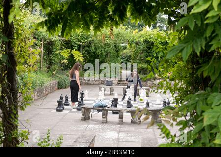 Due donne che giocano una partita di scacchi giganti in un cortile all'aperto nei giardini della Burton Agnes Hall nello Yorkshire Foto Stock