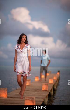 Giovane coppia su un molo al tramonto con lanterne di carta incandescente. Foto Stock