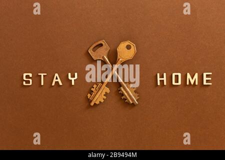 Le parole rimangono a casa fatte da lettere di legno e due chiavi, concetto di auto quarantena a casa come misura preventiva contro il virus corona Covid 19 outbr Foto Stock
