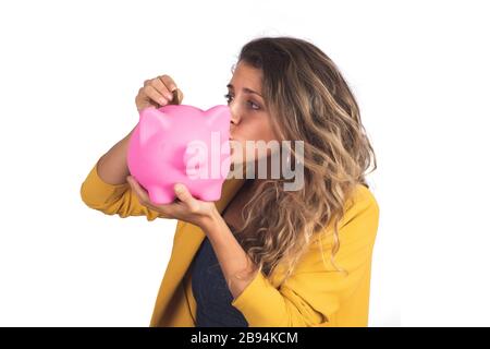 Ritratto di giovane bella donna che tiene e bacia una banca del piggy sullo studio. Isolato sfondo bianco. Concetto di risparmio. Foto Stock