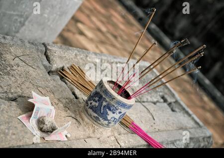 Incenso bastoni che bruciano e offrono nella tomba di Tu Duc, Hue, Vietnam Foto Stock