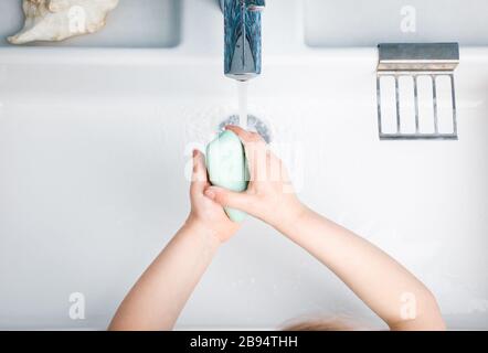 Bambino lavando le mani con sapone ed acqua che effettua le misure protettive di base contro la diffusione dell'epidermide di coronavirus Foto Stock