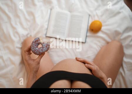 Donna incinta con dolce dolce leggere un libro Foto Stock