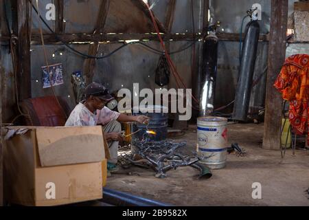 Saldatore nell'impresa sociale e solidale della lavorazione del metallo con materiale riciclato creato da Violette e Dieudonne ad Antananarivo Foto Stock