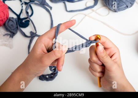 Palle di filato di colore diverso. Le mani dei bambini sono accovacciate e la vista del filo da sopra sul tavolo bianco Foto Stock