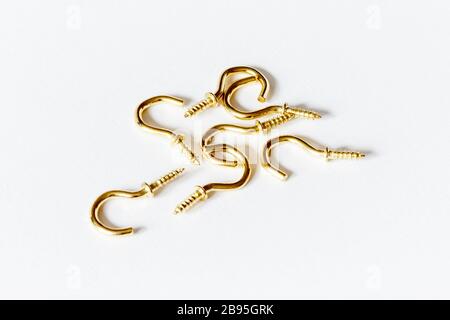 Un mucchio di sette ganci a vite in ottone color oro su sfondo bianco Foto Stock