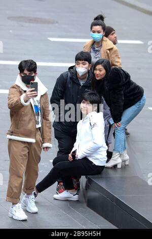 Un gruppo di turisti che indossano maschere prende selfie dopo lo scoppio della malattia di coronavirus a New York City, New York, giovedì 19 marzo 2020. Foto Stock