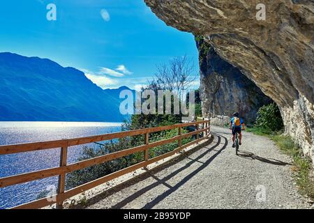 Ciclisti in bicicletta lungo la via ponale a Riva del Garda Foto Stock