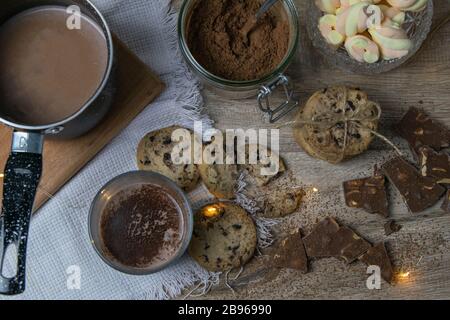 Su un tavolo di legno si trova cacao con marshmallows e forno al cioccolato e fette di cioccolato Foto Stock