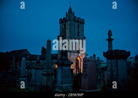 Vecchio castello cimitero di Moody al crepuscolo ora blu con luce arancione acceso. Sterling, Scozia. Foto Stock