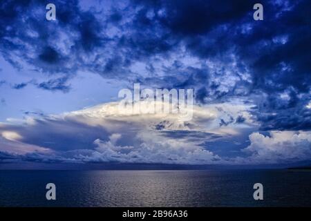 Corpi unici di cumuli tuorbiere nuvole sopra le acque oceaniche linea orizzonte in blu cielo sfondo. Ambiente clima concetto Foto Stock