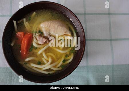 Zuppa di spaghetti di pollo in una ciotola di ceramica marrone. Alimenti biologici sani. Tagliatelle con pollo e verdure Foto Stock