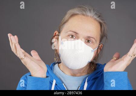 Donna con maschera che solleva le mani a fronte di coronavirus pandemico COVID-19 Foto Stock