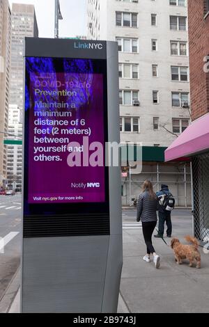 LinkNYC digital Kiosk segno sul marciapiede che mostra Covid-19 (coronavirus) consigli e suggerimenti sulla distanza sociale per i newyorkesi. Foto Stock