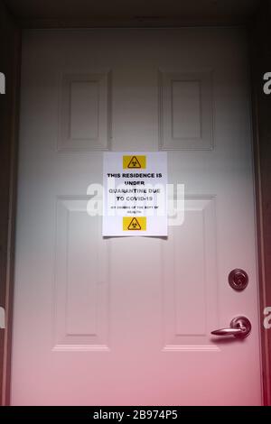 Una residenza autoisolante con un cartello di quarantena sulla porta anteriore che segnala il virus Covid-19. Foto Stock