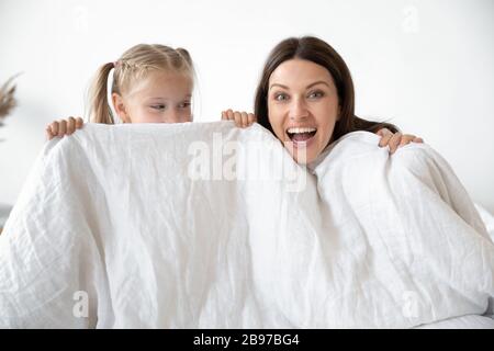 Ritratto di mamma sorridente e bambina che giocano a letto Foto Stock