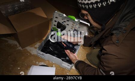 Strasburgo, Francia - 3 marzo 2020: Test start button - vista aerea del lavoratore maschile unboxing pacco contenente nuovo miglior della categoria uso multiplo Festool ROTEX RO 90 DX FEQ-Plus Sander Foto Stock