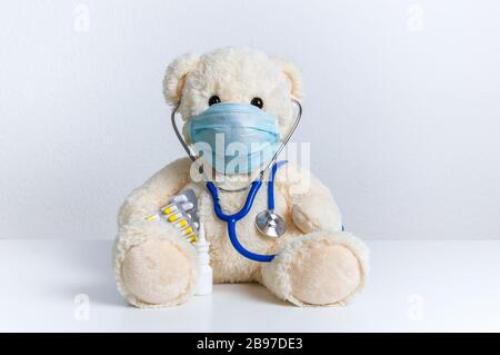 Cute orsacchiotto medico con maschera medica protettiva, stetoscopio e medicina. Concetto di trattamento pediatrico, igiene, protezione da epidemie e virus Foto Stock