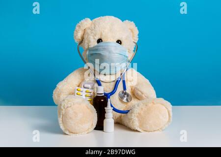 Medico orso Teddy con maschera medica, stetoscopio e medicina: Pillole, spray nasale e flacone. Concetto di malattia, pediatria, igiene e protec virus Foto Stock