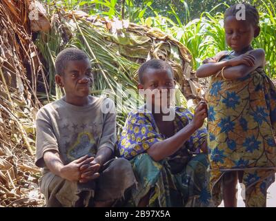 Famiglia di pigmi Mbuti della foresta pluviale Ituri DRCongo seduta al di fuori della loro capanna di foglie. Foto Stock