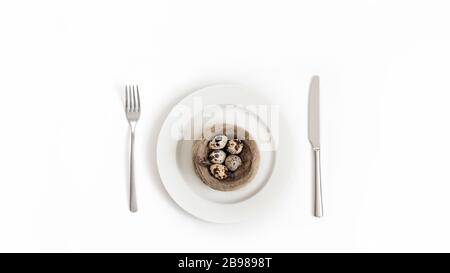 Tavola di Pasqua con uova di quaglia in un nido su uno sfondo bianco. Spazio copia, vista dall'alto, disposizione piatta. Foto Stock