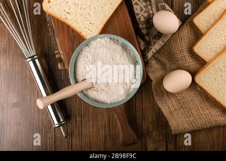 Ciotola di farina con uova e fette di pane Foto Stock