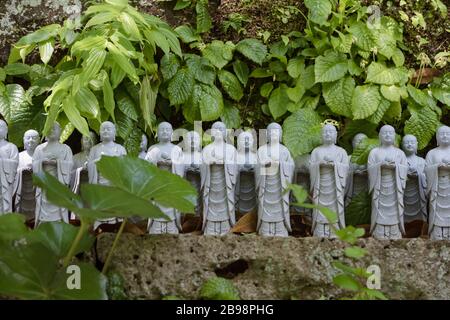 Kamakura, Giappone - 19 maggio 2019: File di statue in pietra Jizo Bodhisattva nel tempio Hase-Dera di Kamakura, Giappone. Jizo è speciale per le donne incinte A. Foto Stock