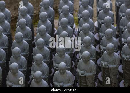 Kamakura, Giappone - 19 maggio 2019: File di statue in pietra Jizo Bodhisattva nel tempio Hase-Dera di Kamakura, Giappone. Jizo è speciale per le donne incinte A. Foto Stock